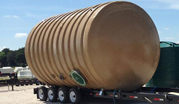 Tan fiberglass tank on trailer en route to wastewater facility.