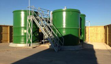 Trio of large green fiberglass water tanks with metal staircase